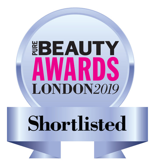 Silver "Pure Beauty Awards London 2019" badge with pink and black text, reading "Shortlisted" on a metallic ribbon at the bottom.