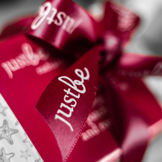 Close-up of a JustBe red ribbon on a blurred background