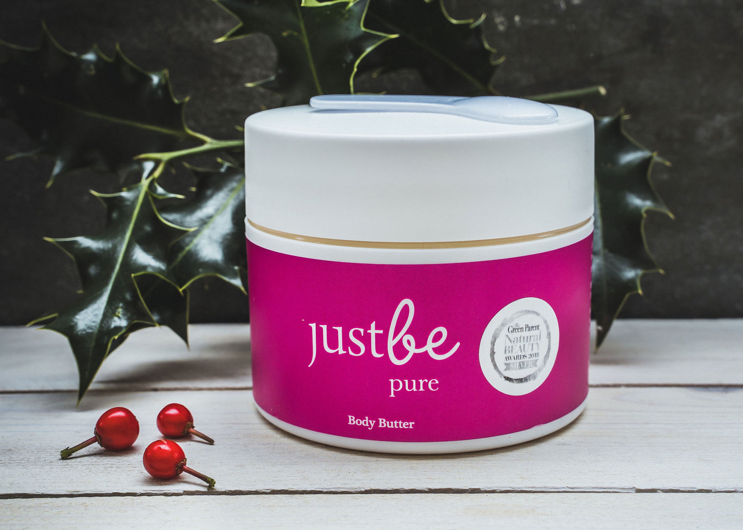 A jar of JustBe Botanicals Luxurious Body Butter with a pink label and Green Parent Natural Beauty award badges displayed.