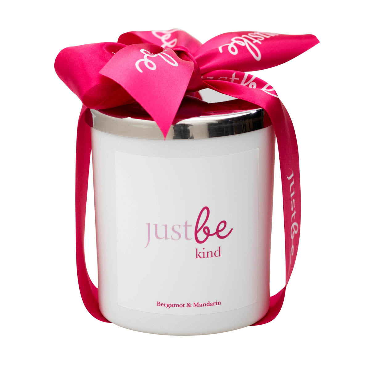 White JustBe Kind candle with silver lid, wrapped in a vibrant pink ribbon featuring the JustBe logo. Label reads "JustBe Kind – Bergamot & Mandarin"