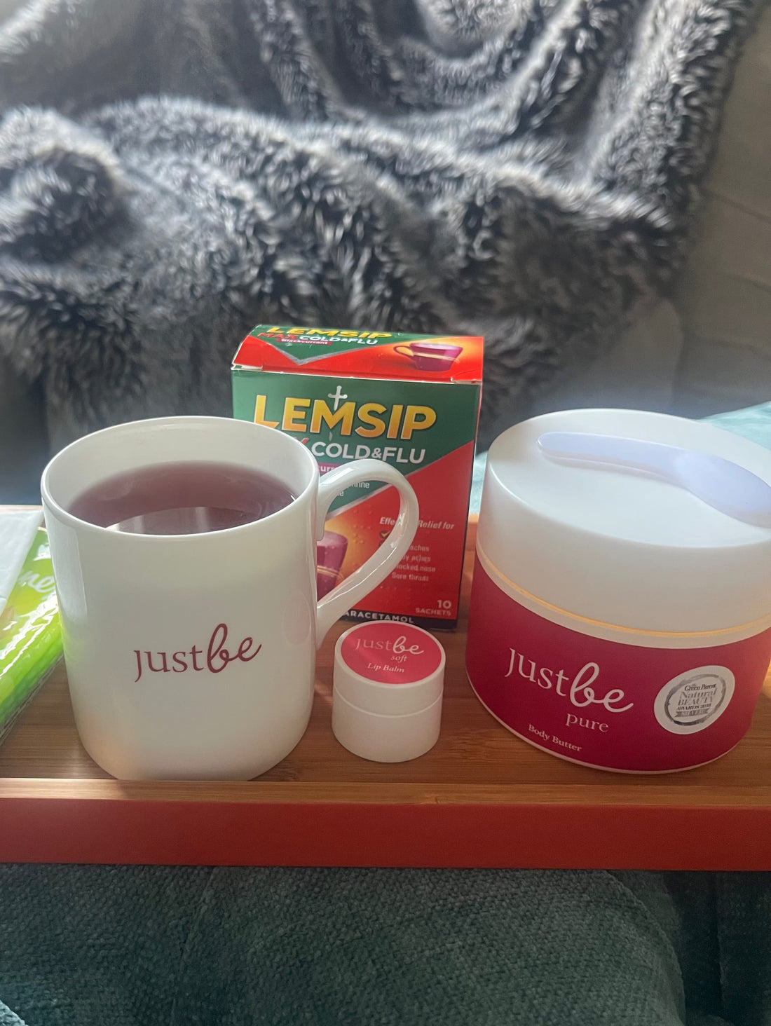 JustBe Botanicals mug beside JustBe Lip Therapy and JustBe Pure BodynButter