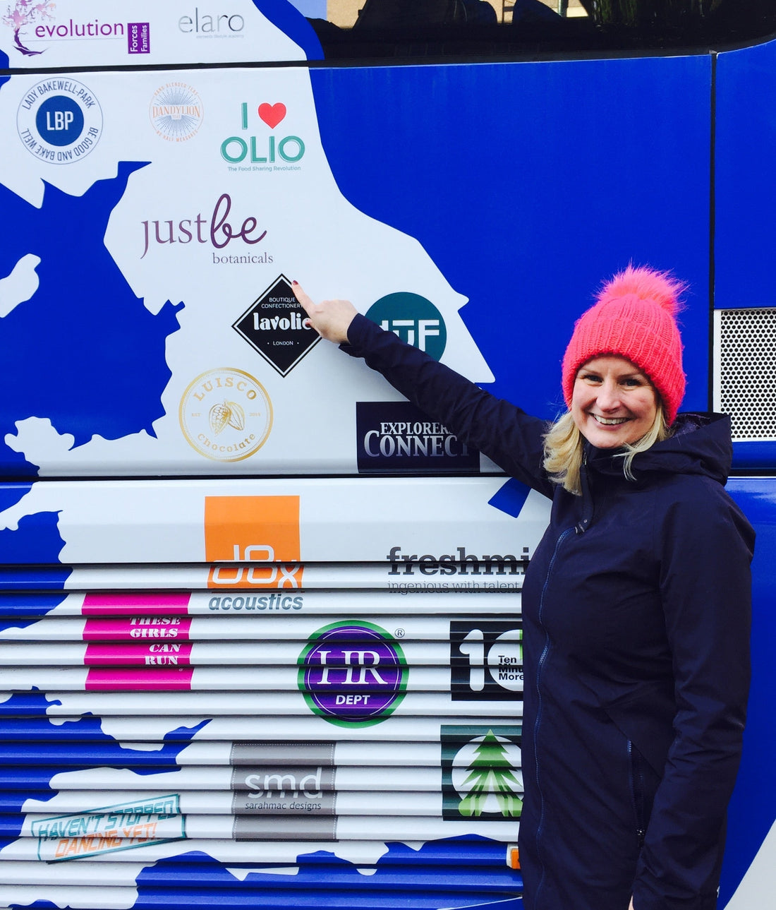 JustBe Botanicals logo on the side of Small Business 100 Bus with Gail Bryden pointing to it