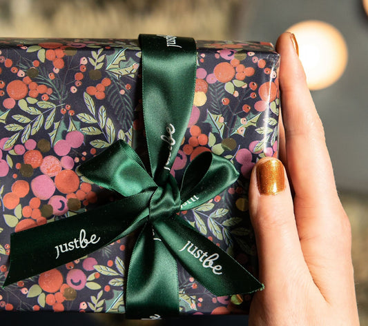 Christmas gift with JustBe ribbon held with lady with gold nail varnish