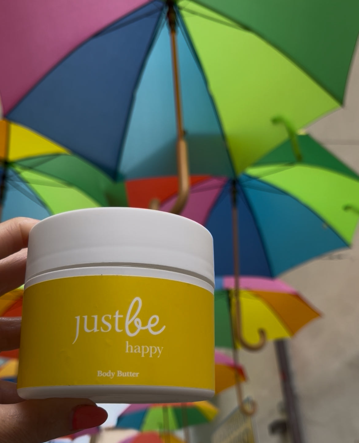JustBe Botanicals Happy Body Butter under colourful umbrellas