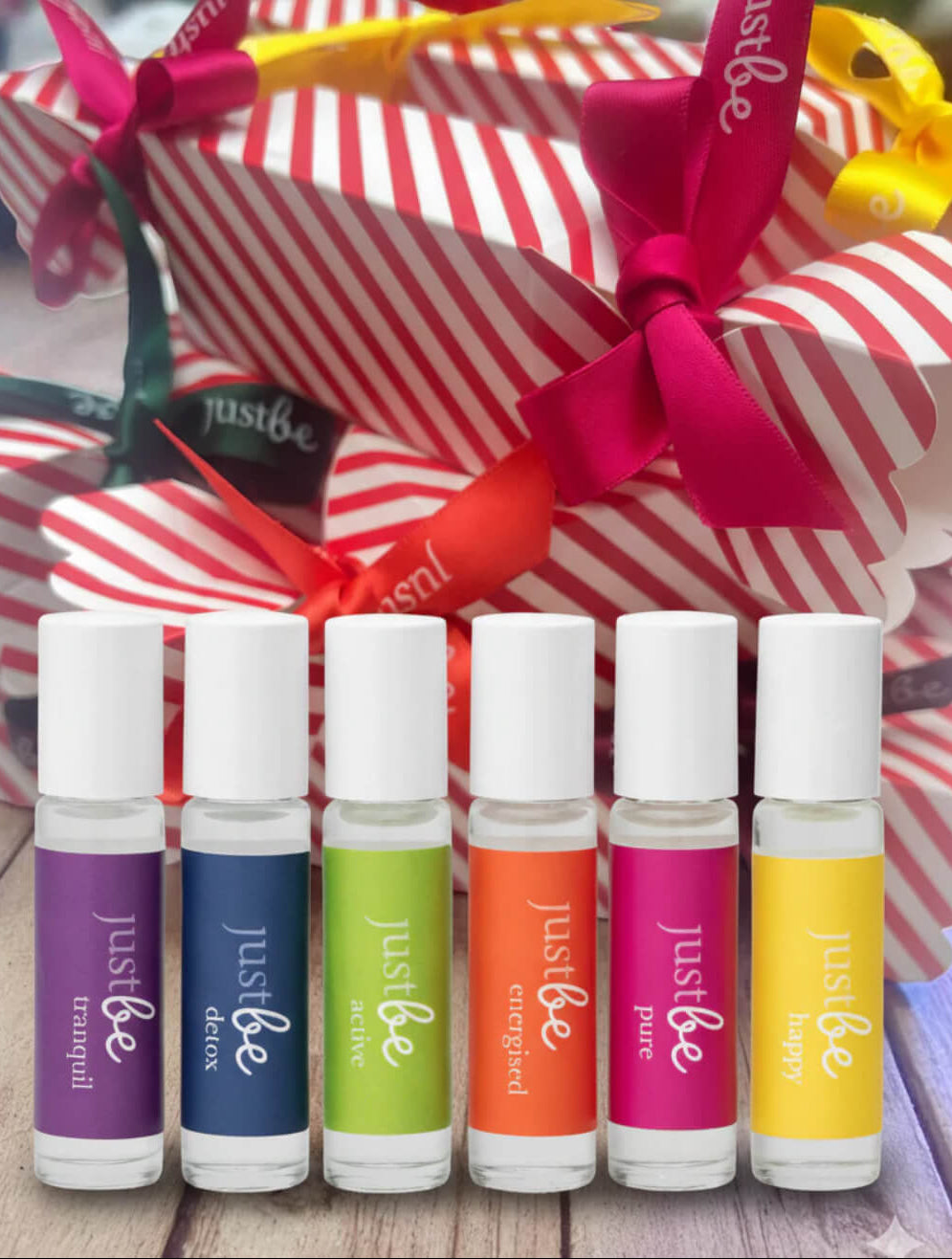 Set of colorful 'justbe' roller bottles with red and white striped Christmas crackers in the background.