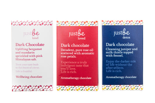 Three JustBe Botanicals dark chocolate bars with different packaging, indicating various flavors within the collection.