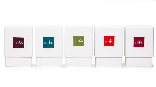 A row of five white boxes, each featuring a different coloured square label with the just be logo - representing the JustBe Inspiration Card sets.