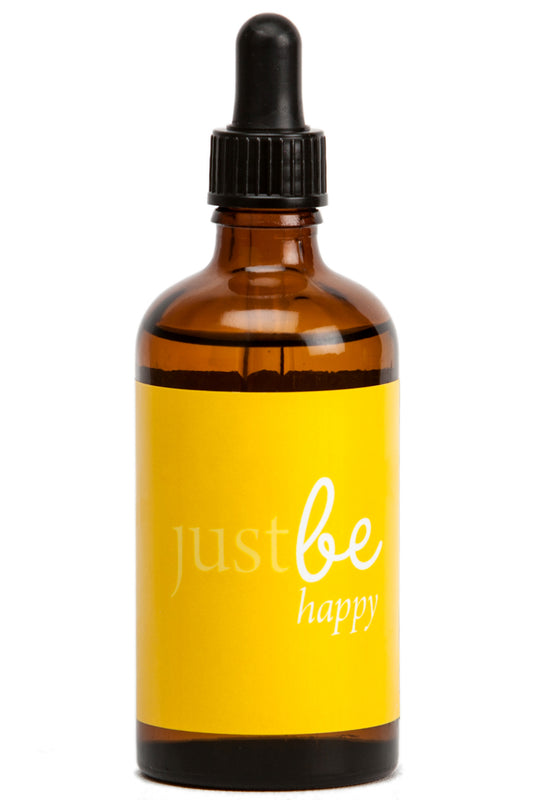 Amber glass bottle of JustBe Happy aromatherapy body and massage oil with bright yellow label and dropper cap.